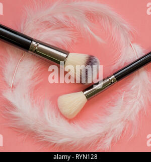 Pinceau à maquillage, maquillage professionnel outils. Pinceau doux et agréables pour le maquillage, concept. Les Pinceaux et plumes blanches sur fond rose Banque D'Images