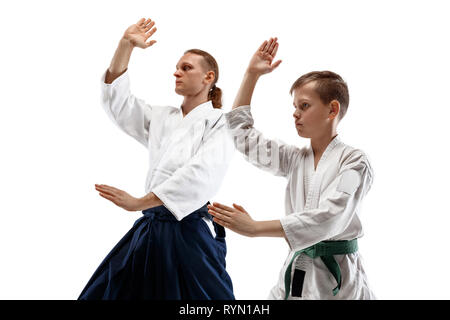 L'homme et la femme qui se bat à l'aïkido en école d'arts martiaux. Style de vie sain et de sport concept. Homme avec barbe en kimono blanc sur fond blanc. Karate femme avec un visage concentré. Banque D'Images