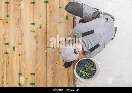 Installateur de plancher de carreaux de céramique. Comme bois à panneaux installés par des professionnels de l'aménagement intérieur Construction caucasienne travailleur. Parquet Industrial Banque D'Images