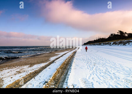 Péninsule Hel (Pologne) en hiver. Sundy beach dans le crépuscule avec un homme et son chien à marcher le long de l'eau Banque D'Images