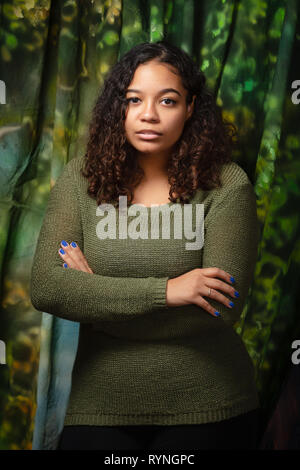 La haute école secondaire biracial attrayants qui pose pour des portraits avec expression grave with arms crossed Banque D'Images