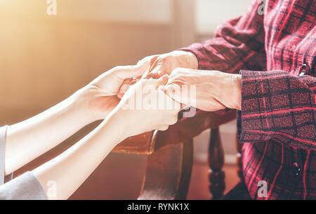 Teenage girl holding asie jeune soignant les mains de grand-mère, du concept d'aider les soins pour les personnes âgées la vie avec arrière-plan sombre, Close up, copy space, cropped Banque D'Images