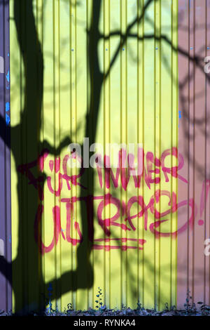 L'ombre des branches et le tronc d'un arbre sur le checker plate d'un immeuble industriel à côté du slogan : Forever Ultras. Banque D'Images