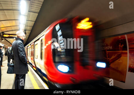 Métro de Londres les navetteurs de la plate-forme pour attendre l'arrivée de train de tube plein de passagers Banque D'Images