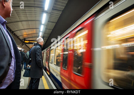 Les banlieusards attendre le train de tube approche plein de passagers Banque D'Images