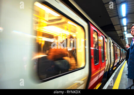 Métro de Londres les navetteurs de la plate-forme pour attendre l'arrivée de train de tube plein de passagers Banque D'Images