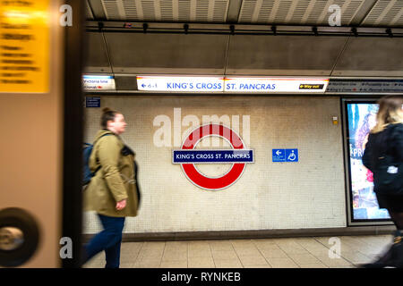 Photographie grand angle de personnes sur la plate-forme et emblématiques du tube circulaire signe sur l'Kings Cross St Pancras, plate-forme souterraine Banque D'Images