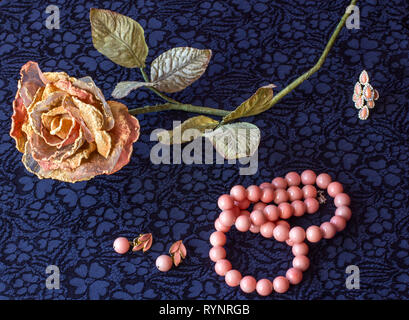 Rose artificielle avec perles rose, sur fond de textiles. Banque D'Images