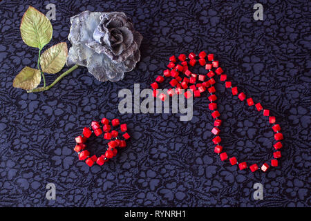 Still Life de rose artificielle avec des perles rouges et bracelet sur fond textile Banque D'Images