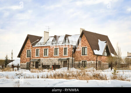 Belle maison de deux étages au bord de la rivière en hiver Banque D'Images