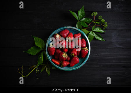 Photo : Contraste des fraises dans une assiette verte sur un tableau noir Banque D'Images