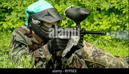 L'homme allongé sur le sol qui vise à une cible avec le paintball 4K FS700 Odyssey 7Q Banque D'Images