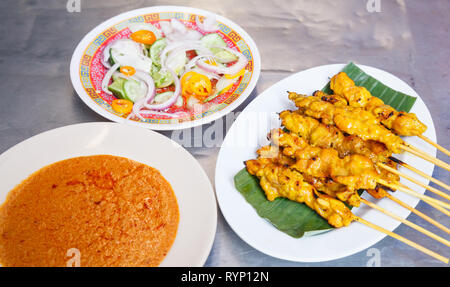 Plat hors-d'œuvre de l'alimentation de rue traditionnels Thaï, recette Satay de Porc Porc grillé stick mise sur des feuilles de banane en plaque blanche servi avec arachides sucrées di Banque D'Images