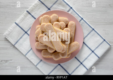 Savoyardi les biscuits sur la plaque rose sur fond de bois blanc, vue du dessus. Mise à plat, les frais généraux, d'en haut. Banque D'Images