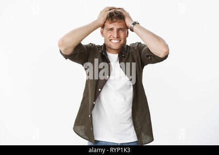 Aïe ça fait mal. Portrait d'intense et troublée mécontent a souligné Guy holding hands on top chef de serrer les dents et les sourcils que voir douloureux Banque D'Images