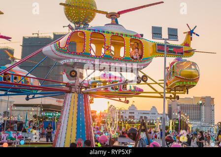 Phnom Penh, Cambodge - 6 Février 2019 : une jeune femme et un enfant ride l'hélicoptère carrousel dans les lumières de coucher du soleil à un parc d'amusement. Banque D'Images