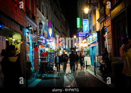 Les touristes passent des boutiques et des cafés comme ils marchent le neon rues tard dans la nuit dans le Quartier Latin de Paris France Banque D'Images