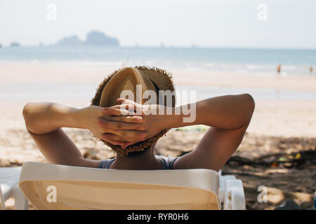 Close-up of young male traveler relaxing et assis sur chaise de plage - été vacances. Banque D'Images