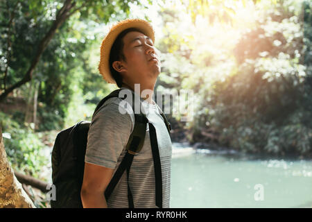 Les jeunes hommes asiatiques traveler bénéficiant et l'inhalation de l'air sain en vert forêt - l'air frais de la nature et de la vie le bien-être. Banque D'Images
