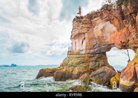 Arch rock dans la mer avec un jeune homme debout sur une jambe sur son sommet. Un concept de remise en forme, yoga, et d'un style de vie sain. Krabi, Thaïlande. Banque D'Images