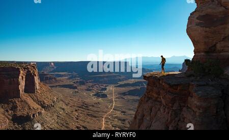 Jeune homme debout au bord d'une falaise sur la fourrure Shafer Canyon Road, Shafer Canyon Overlook, Island in the Sky Banque D'Images