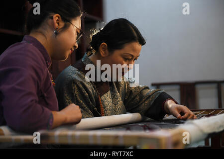 (190315) -- SHANGHAI, 15 mars 2019 (Xinhua) -- Fu Xianghong (R) et sa fille Fu Hanlu communique sur les techniques de broderie en 101 dans la ville de Suzhou Wuzhong District, Province de Jiangsu Chine orientale, le 14 mars 2019. Xianghong Fu Fu Hanlu et sa fille ont été d'une longue lignée de broderie. En 2015, Fu Xianghong a été nommé en tant que représentant maître de Suzhou broderie, qui a été répertorié comme l'un des patrimoines immatériels de Suzhou. Ses œuvres de style unique combinant l'aspect pratique et l'art ont été présentés au cours de la Semaine de la mode de Beijing et Fashion Week de Paris. Sa fille Hanl Fu Banque D'Images