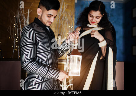 Happy diwali jour ! Joli couple indien dans l'amour, à l'usure et élégant costume, saree posés sur restaurant et organiser ensemble la lanterne. Banque D'Images