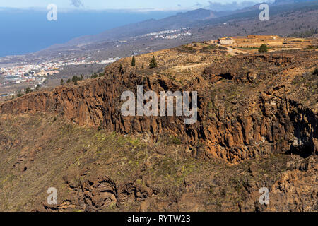 Voir dans le Barranco de Guaria et une ferme finca à distance au-dessus de la falaise, et les falaises de Los Gigantes sur l'horizon, à partir de Las Fuentes Banque D'Images