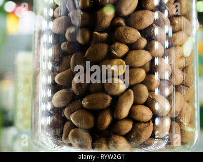 Mélange de noix dans un bocal en verre, noisettes, amandes, noix de cajou sur fond blanc. Selective focus, copiez l'espace. Banque D'Images