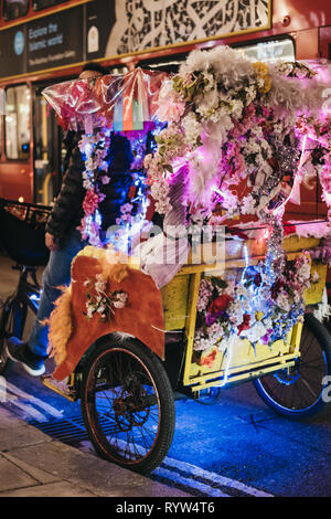 Londres, UK - 9 mars, 2019 : rickshaws colorés décorées de fleurs sur Oxford Street, Londres, dans la nuit. Oxford Street si l'un des plus célèbres str Banque D'Images