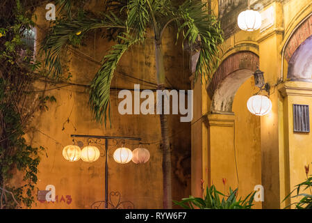Vieille ville de Hoi An, Vietnam la nuit. Shabby murs jaunes, lanternes traditionnelles, et d'un palmier. Banque D'Images