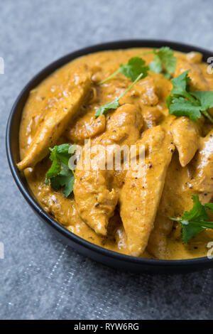 Close up avec vue latérale d'un bol de curry de poulet kurma. Bol de curry Indien d'épaisseur. Bol de poulet korma curry épais avec fond gris. Banque D'Images