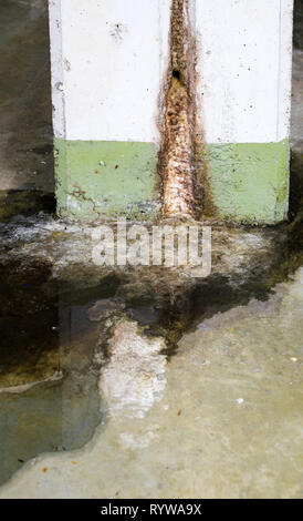 Dommages causés par l'eau dans la construction en béton avec du calcium et de dépôts de rouille et de flaques près d'un mur de soutènement pilier dans un garage Banque D'Images