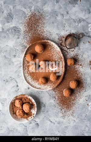 Chocolat cru bliss balls saupoudrés de cacao sur une plaque blanche de forme irrégulière Banque D'Images