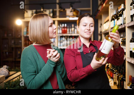 Photo de jeunes femmes avec une bouteille de vin dans les mains dans un magasin Banque D'Images