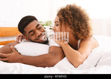 Loving black couple relaxing in bed at home Banque D'Images