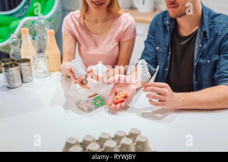 Le recyclage, la réutilisation. View of a young couple holding piles, ampoules dans les mains Banque D'Images