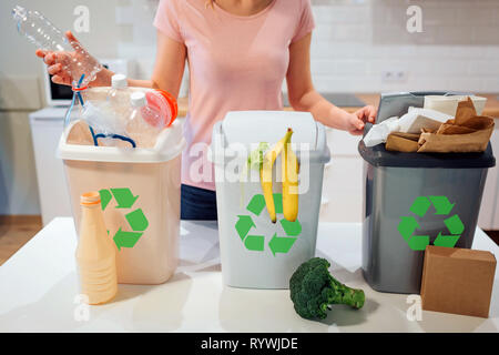 Le tri des déchets à la maison. Le recyclage. Woman putting bouteille plastique dans la poubelle dans la cuisine Banque D'Images