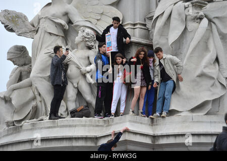 Les élèves l'ascension de la Queen Victoria Memorial à l'extérieur de Buckingham Palace à Londres pendant la grève de l'école pour le changement climatique. Banque D'Images