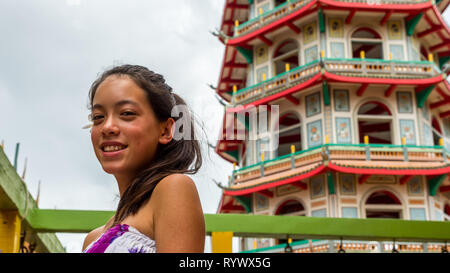 Jeune fille en robe mauve et blanc debout devant temple Banque D'Images