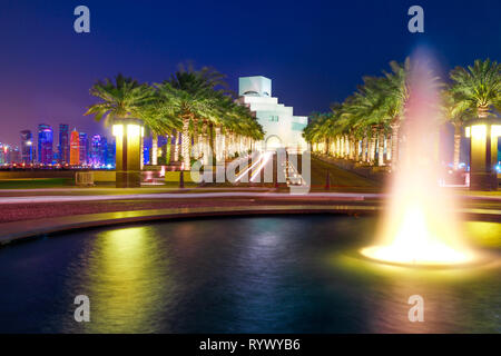 Fontaine eau reflétant près de corniche avec des gratte-ciel de West Bay skyline éclairé à l'arrière-plan. Doha, capitale du Qatar, en Moyen Orient, Arabe Banque D'Images