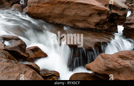 L'eau qui coule en cascade et à travers une fente de la pierre de sable canyon. Effet d'eau soyeuse avec de l'eau bleu. Banque D'Images
