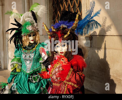 Les gens vêtus de masques traditionnels et des costumes pour le Carnaval de Venise en vertu de l'article à l'arche du Palais des Doges, de la Piazza San Marco, Venice, Veneto, Italie Banque D'Images