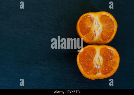 Les satsumas/orange/clémentine close up sur un fond d'ardoise sombre réduit de moitié Banque D'Images