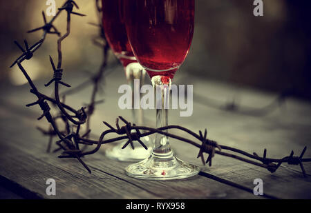 Lunettes avec boisson alcoolisée et un fil de fer barbelé rouillé sur une table en bois. La dépendance alcoolique. Banque D'Images