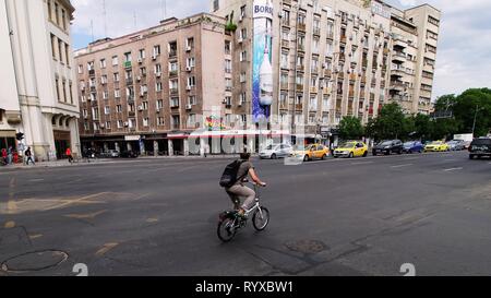 Bucarest, Roumanie - 16 mai 2018 : une femme à vélo sur un boulevard dans le centre-ville de Bucarest, Roumanie. Banque D'Images