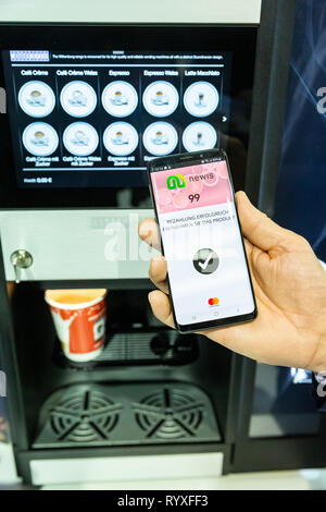 Hambourg, Allemagne. Mar 15, 2019. Dans le cadre du salon de la gastronomie et de l'hôtellerie dans l'Internorga Hamburg salles d'exposition, l'employé utilise son téléphone portable pour payer son café. Cette année, les principaux thèmes sont 'snacking', restaurants d'entreprise commune et la gastronomie. À partir de la 15e à la 19e. Autour de 95000 visiteurs professionnels sont attendus en mars 2019. Credit : Ulrich Perrey/dpa/Alamy Live News Banque D'Images