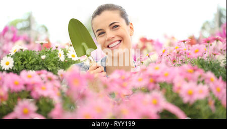 Smiling woman in jardin de fleurs avec des outils de jardin, concept de printemps Banque D'Images