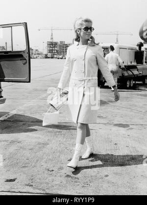 Catherine Deneuve, arrivant à l'aéroport de Londres portant un habit carré blanc avec des bottes blanches, vers 1964 référence #  33751 933 THA Banque D'Images