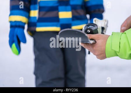 Szklarska Poreba, Pologne - Février 2019 : moniteur de ski holding skis petit garçon et lui expliquant les caractéristiques de sécurité de l'équipement Banque D'Images